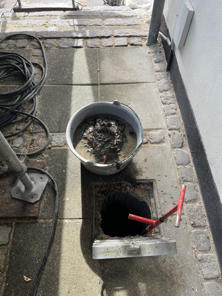 Opsamlet materiale og åben sandfangsbrønd under rensning på kommunal bygning